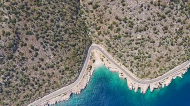 Altın plaj ve mavi deniz yukarıdan görünüyor. 4K 'da sahil yolu var.