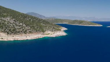 4K kıyı manzaralı, kıyı yolunun yanında altın kum ve mavi su var.