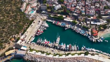 Turkuaz suyu ve güneşli bir körfezde rıhtıma yanaşmış yatları olan sahili..