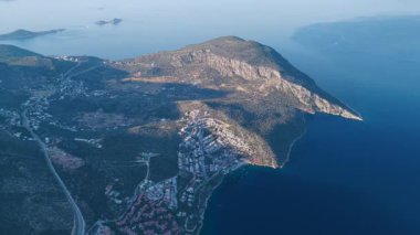 Evler, palmiye ağaçları ve deniz yumuşak ışık altında.