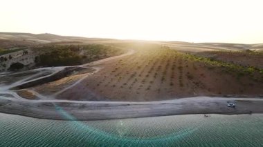 Uzun nehir, günbatımı tarlalarında esiyor. 4K parlayan alanlar ve suyun yumuşak yansımaları videosu