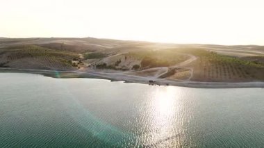 Tarlalar alacakaranlıkta bir nehirde. 4K görüntüleri sessiz tarım arazilerini sıcak gün batımı ve sakin sularla yakalıyor