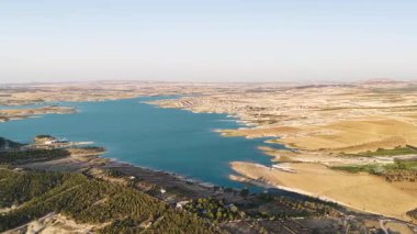 Tarlalar ve nehir alacakaranlıkta altın rengini yansıtır. Geniş kırsal arazinin 4K görüntüsü