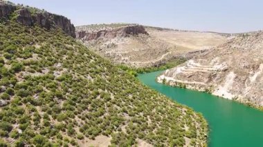 Çerçevede kıvrımlı nehir, kayalıklar ve jet ski var.