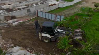 İşçiler zemini düzleştirmek için traktörü kullanırlar ve sağlam bir inşaat temeli oluştururlar..