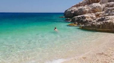 Sessiz bir Akdeniz kıyısı üzerinde güneşin tadını çıkaran manken manzarası.