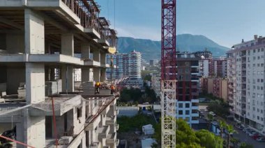 Bir gökdelen vinç gibi şekil alır. Taşıma malzemeleri ve işçiler beton seviyesinde.