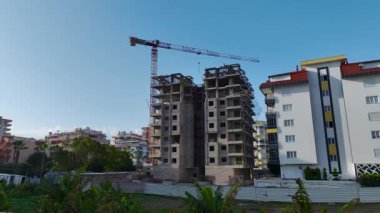 İşçiler yapısal istikrarı sağlarken, inşaat vinci malzemeleri kaldırır.