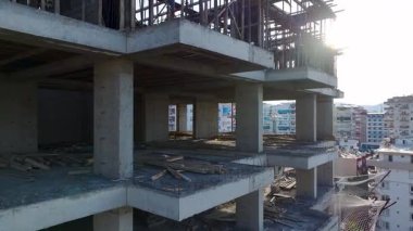 İşçiler takviye kuvvet ve vinç nakil malzemeleri kurarken yüksek katlı bir bina şekilleniyor.