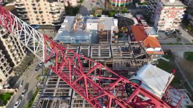 Vinçler ağır malzemeleri taşırken, inşaat işçileri yeni bina iskeletini takviye ediyor.