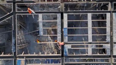 İşçiler binanın yapısını şekillendirirken vinçler ve mühendisler malzemeleri yönetirler..