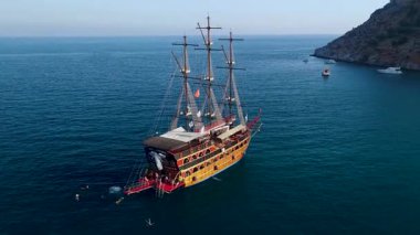 Korsanlar gibi giyinmiş insanlar kıyıda su kenarında yürürler..