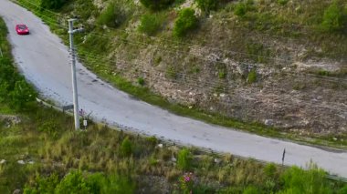 Üstü açık, kadın modelli. Manzaralı yolda ilerliyor.