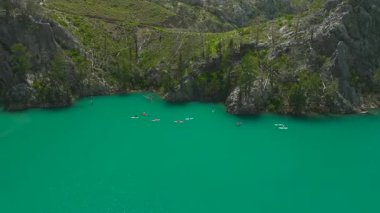 İnsanlar yeşil suyla kanyonda SUP sörfü yapıyor.