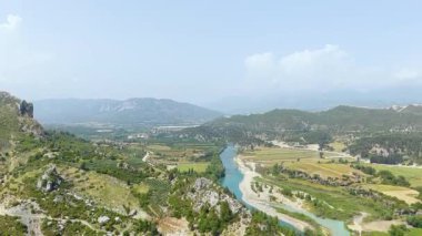 Drone görüntüsü nehir boyunca çiftlikler ve yeşilliklerle hareket eden jet ski gösteriyor..