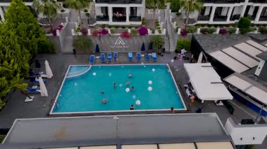 Yamaçtaki villaların ve yüzücülerin geniş açılı görüntüsü..