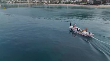 Drone görüntüsü kıyıya yakın hareket eden küçük bir balıkçı teknesi gösteriyor..
