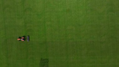Drone görünümü çim biçme makinesinin yeşil futbol sahasını kestiğini gösteriyor.