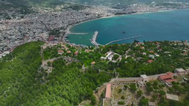 İnsansız hava aracı görüntüleri kayalık tepelerin yakınındaki kasaba binalarını gösteriyor..