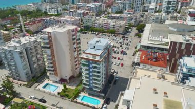 İnsansız hava aracı deniz kenarında havuzlu, slaytlı ve aile arazili mülkler gösteriyor.