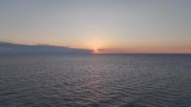 Hava görüntülerinde gök mavisi su ve sakin kumlu sahil görünüyor..