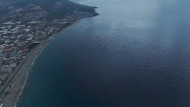 İnsansız hava aracı görüntüsü sakin kıyı şeridini parlak suyla gösteriyor.