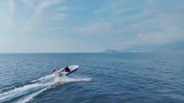 Güneş ışığında limana yaklaşan küçük geminin üst görüntüsü.