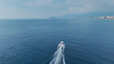 İnsansız hava aracı açık gökyüzünün altında limana giden bir tekne gösteriyor..