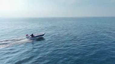 Parlak gökyüzünün altındaki açık denizdeki geminin drone görüntüsü.