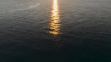 Sakin dalgalar alacakaranlıkta kumlu sahile dokunur.