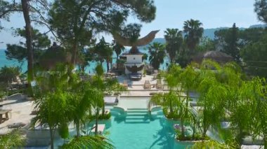 Palmiye ağaçlarının altında deniz kenarındaki rahatlama manzarası.