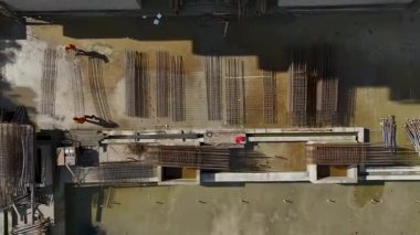 İnşaat alanında metal takviyesi hazırlayan iki işçi.