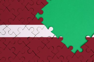 Letonya bayrağı tamamlanmış bir jigsaw bulmaca ücretsiz yeşil kopya alanı sağ tarafında ile tasvir edilir.
