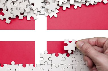 Danimarka bayrağı üzerinde insan el kıvrımlar bir bulmaca beyaz renk bir tablo üzerinde tasvir.