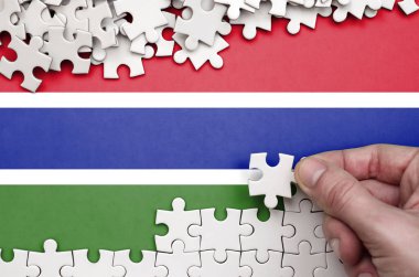 Gambiya bayrağı üzerinde insan el kıvrımlar bir bulmaca beyaz renk bir tablo üzerinde tasvir.