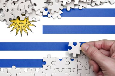 Uruguay bayrağı üzerinde insan el kıvrımlar bir bulmaca beyaz renk bir tablo üzerinde tasvir.