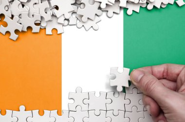 Fildişi Sahili bayrağı üzerinde insan el kıvrımlar bir bulmaca beyaz renk bir tablo üzerinde tasvir.