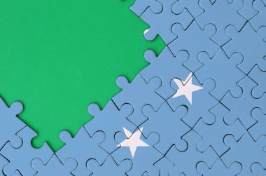 Mikronezya bayrağı tamamlanmış bir jigsaw bulmaca ücretsiz yeşil kopya alanı sol tarafında ile tasvir edilir.