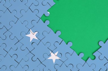 Mikronezya bayrağı tamamlanmış bir jigsaw bulmaca ücretsiz yeşil kopya alanı sağ tarafında ile tasvir edilir.