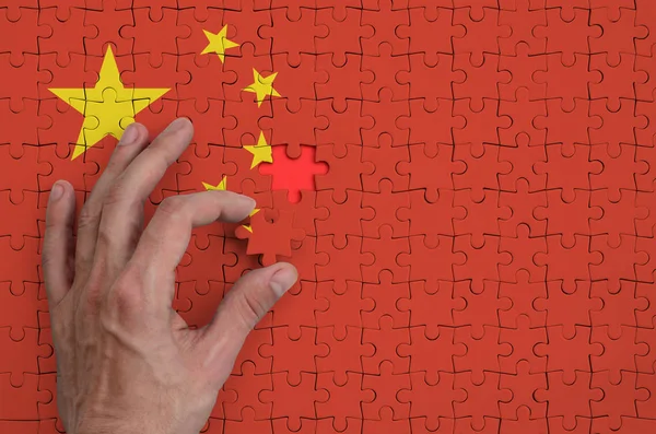 中国国旗描绘在一个谜题 该名男子的手完成折叠 — 图库照片