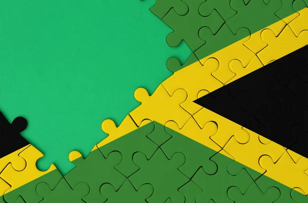 ジャマイカ国旗は 左側にある緑の無料コピー スペースを持つ完成したジグソー パズルに描かれています — ストック写真