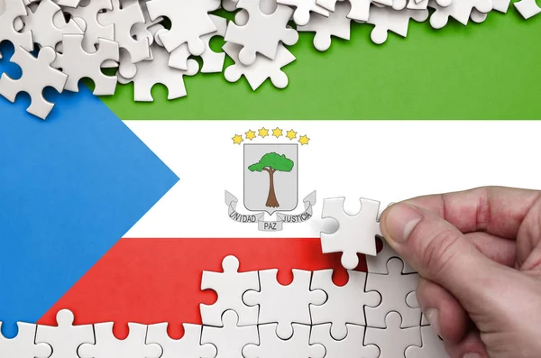 Ekvator Ginesi bayrağı üzerinde insan el kıvrımlar bir bulmaca beyaz renk bir tablo üzerinde tasvir.