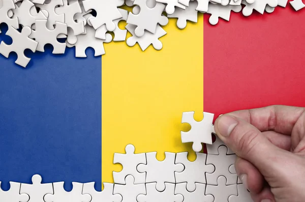罗马尼亚国旗描绘在一张桌子上 上面的人手折叠着白色的拼图 — 图库照片