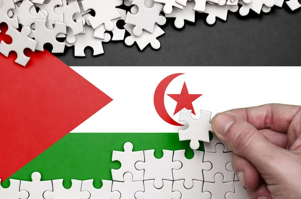 Batı Sahra bayrağı üzerinde insan el kıvrımlar bir bulmaca beyaz renk bir tablo üzerinde tasvir.