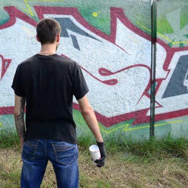 Genç mecnuna bir sprey ile standları bir beton duvara grafiti boya ile olabilir. Yasadışı vandalizm kavramı. Sokak sanatı.