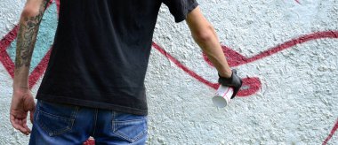 Genç mecnuna beton duvara grafiti boyar. Yasadışı vandalizm kavramı. Sokak sanatı.