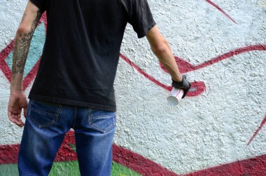 Genç mecnuna beton duvara grafiti boyar. Yasadışı vandalizm kavramı. Sokak sanatı.