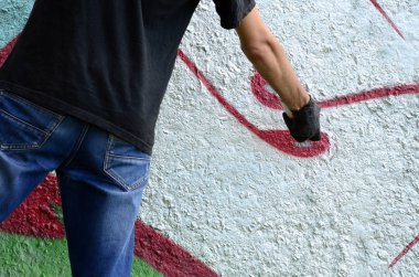 Genç mecnuna beton duvara grafiti boyar. Yasadışı vandalizm kavramı. Sokak sanatı.