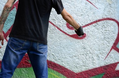 Genç mecnuna beton duvara grafiti boyar. Yasadışı vandalizm kavramı. Sokak sanatı.