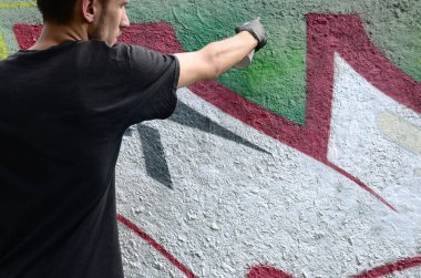 Genç mecnuna beton duvara grafiti boyar. Yasadışı vandalizm kavramı. Sokak sanatı.